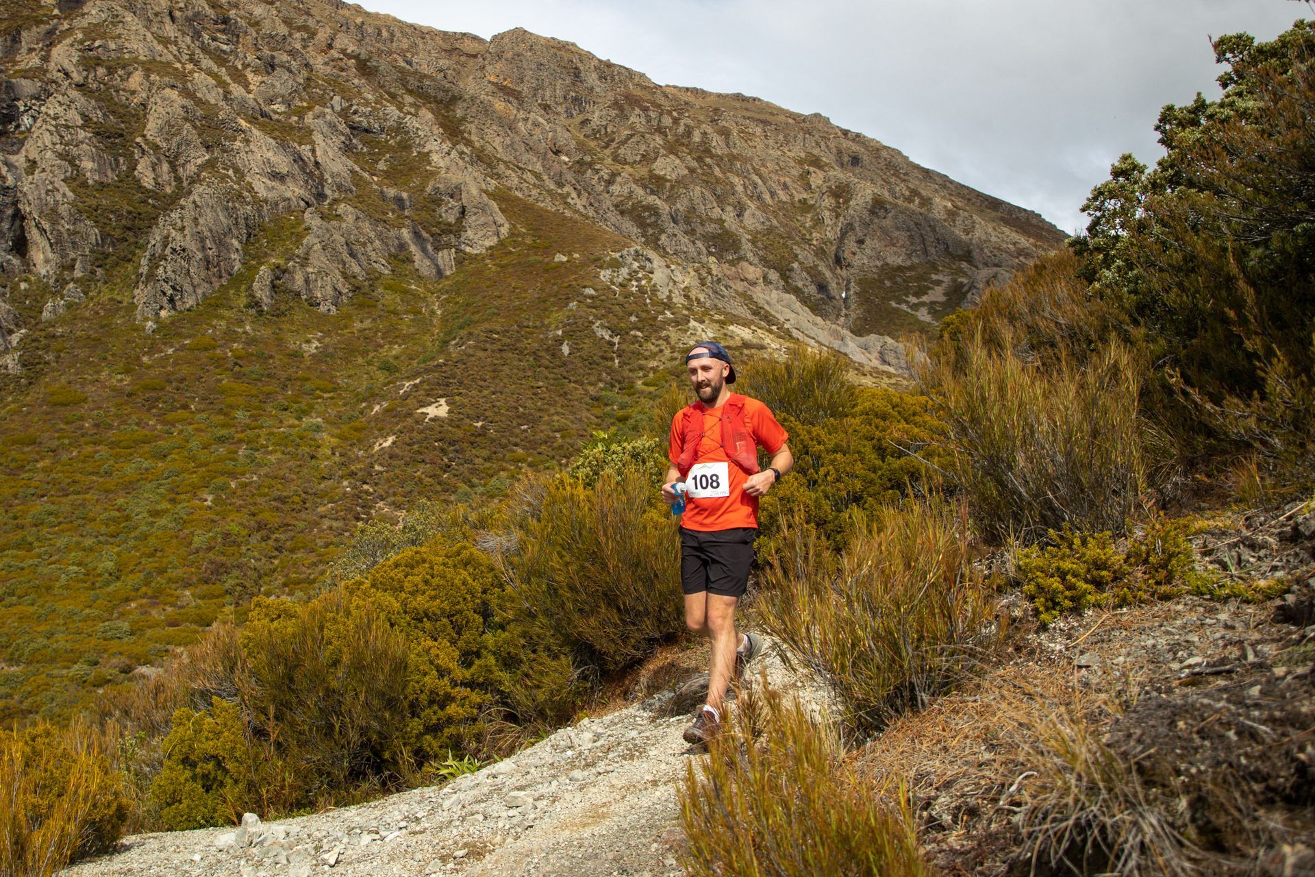 A man is running on a trail in the mountains.