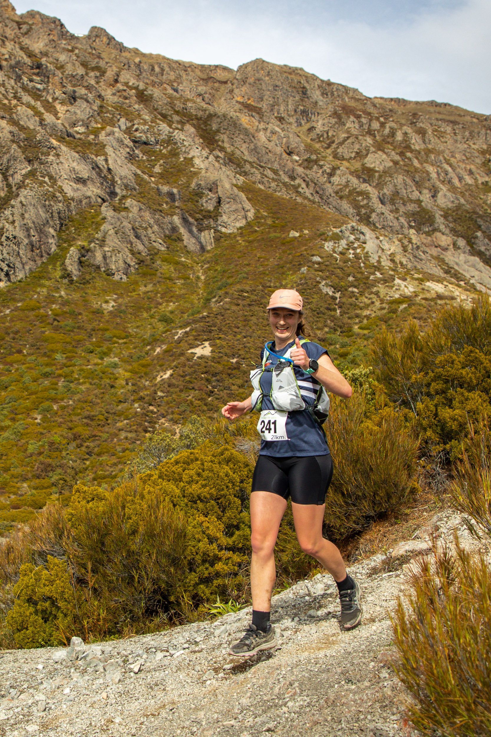A woman is running on a trail in the mountains.