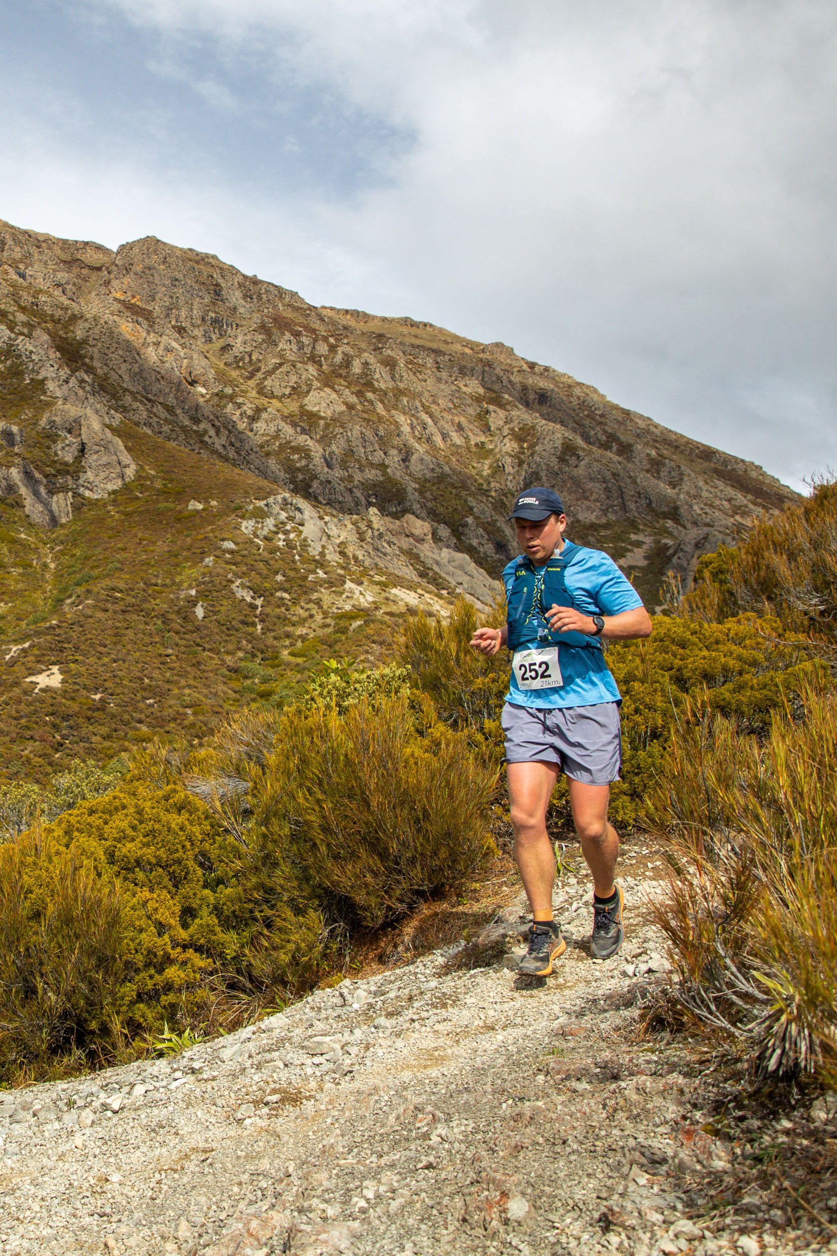 A man is running on a trail in the mountains.
