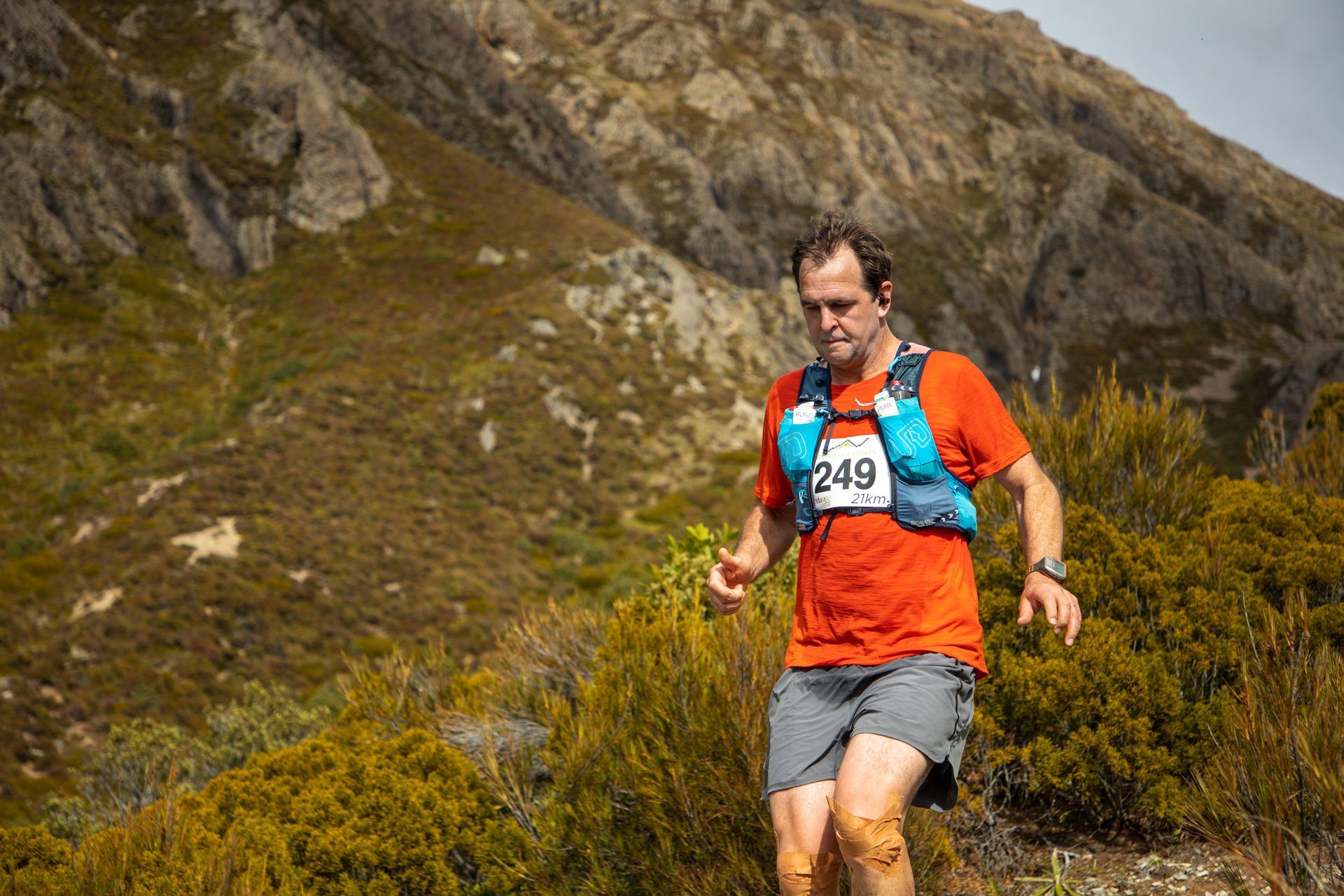 A man is running on a trail in the mountains.