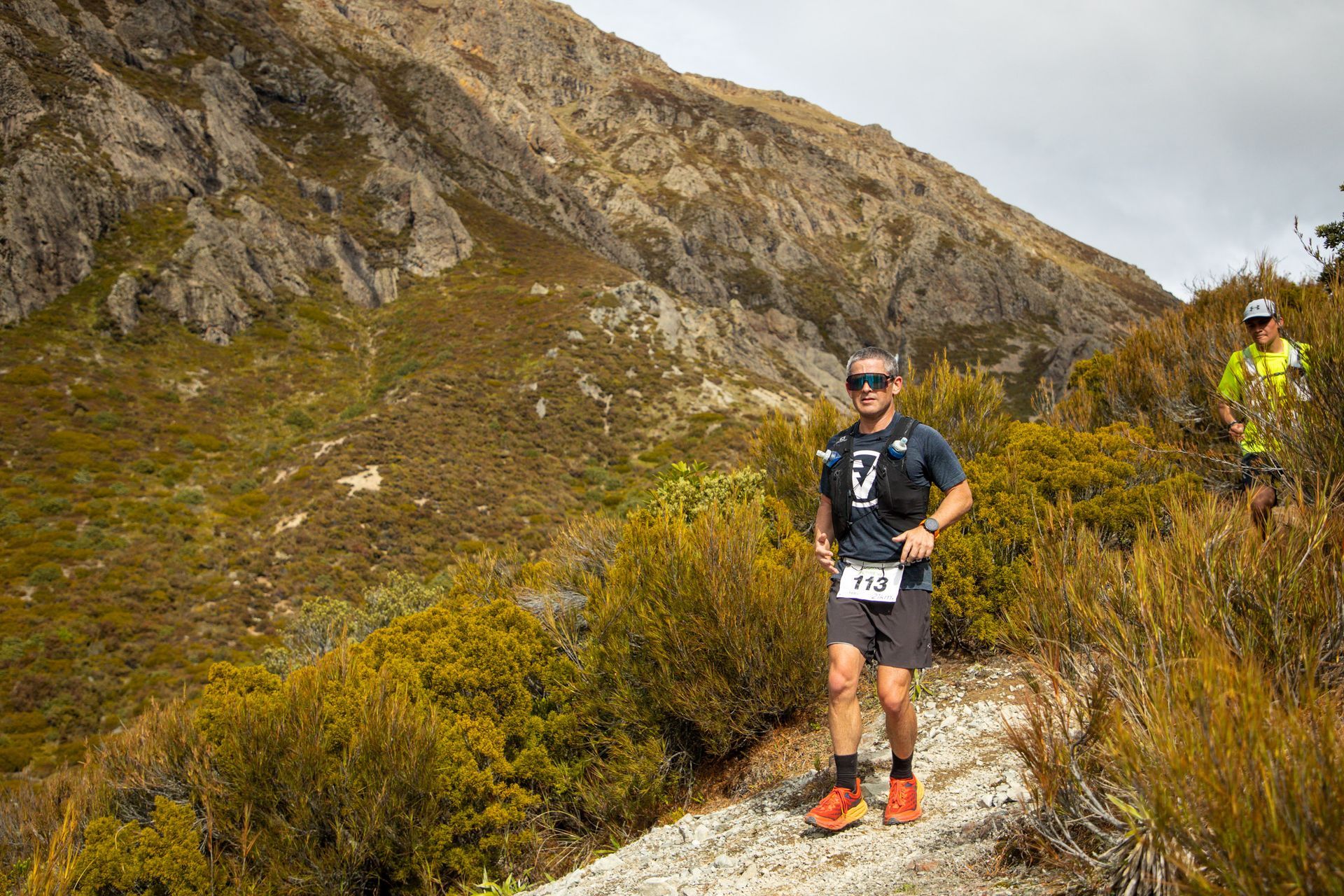 A man is running on a trail in the mountains.