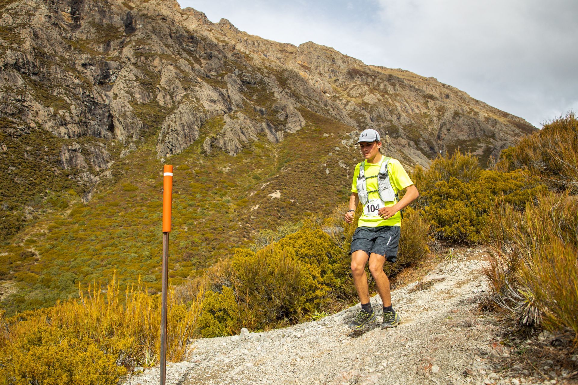 A man is running on a trail in the mountains.