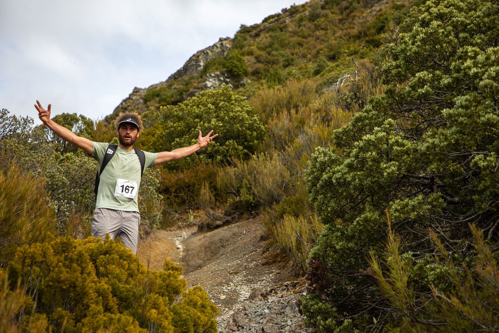A man is standing on top of a hill with his arms outstretched.