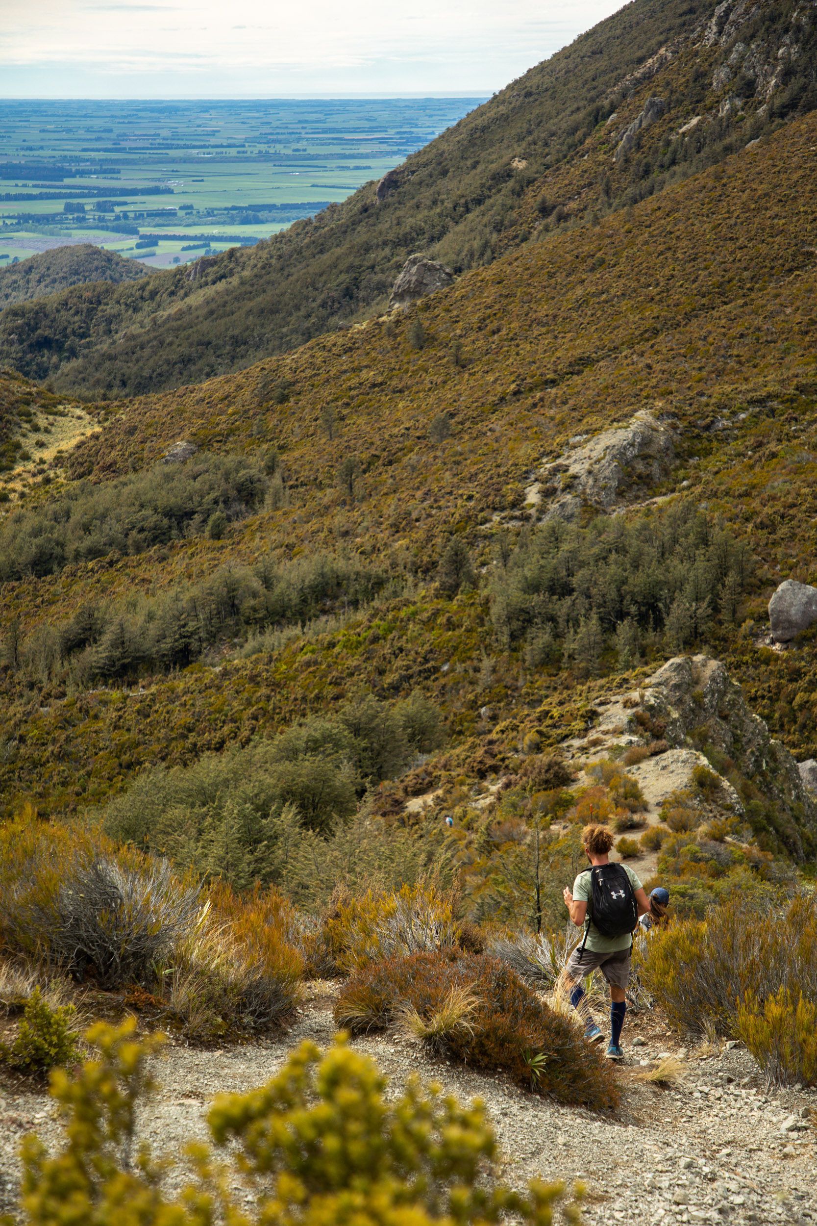 A man is hiking up a hill with a backpack.