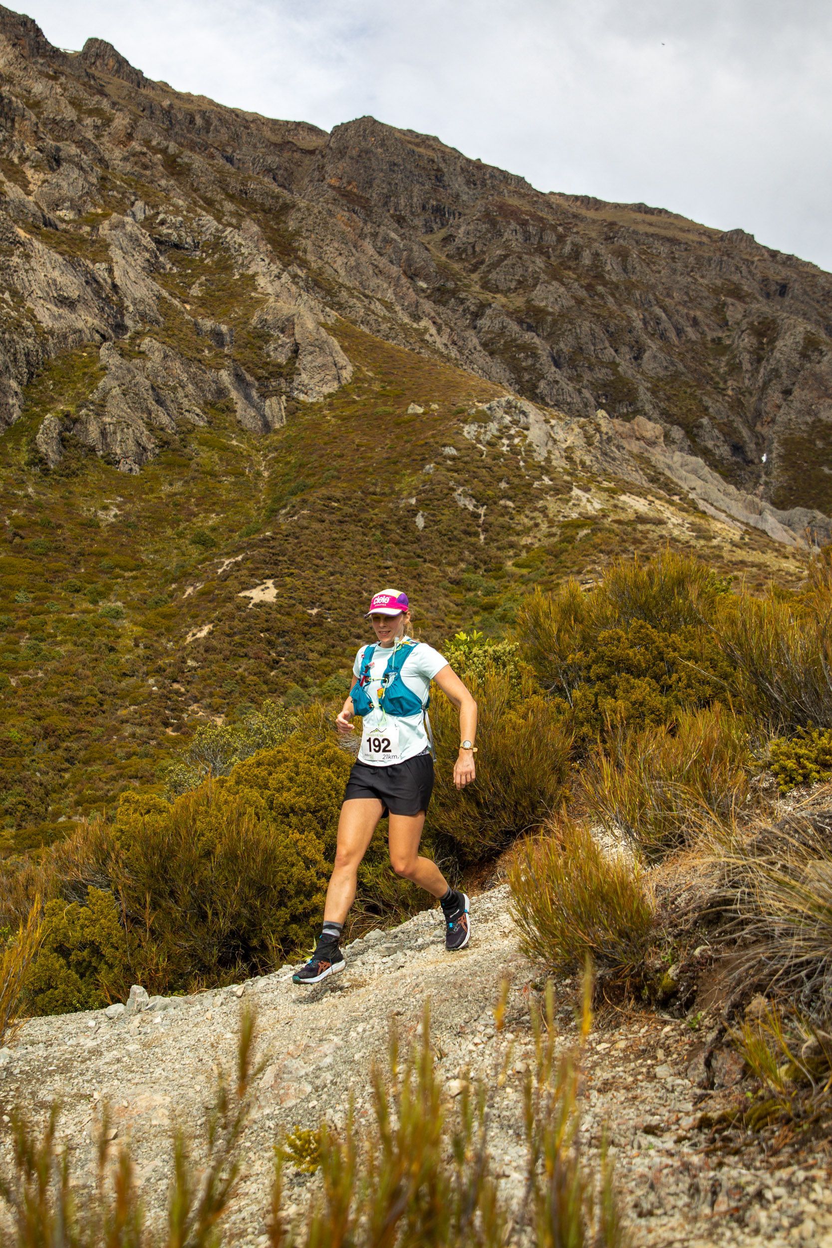 A woman is running on a trail in the mountains.