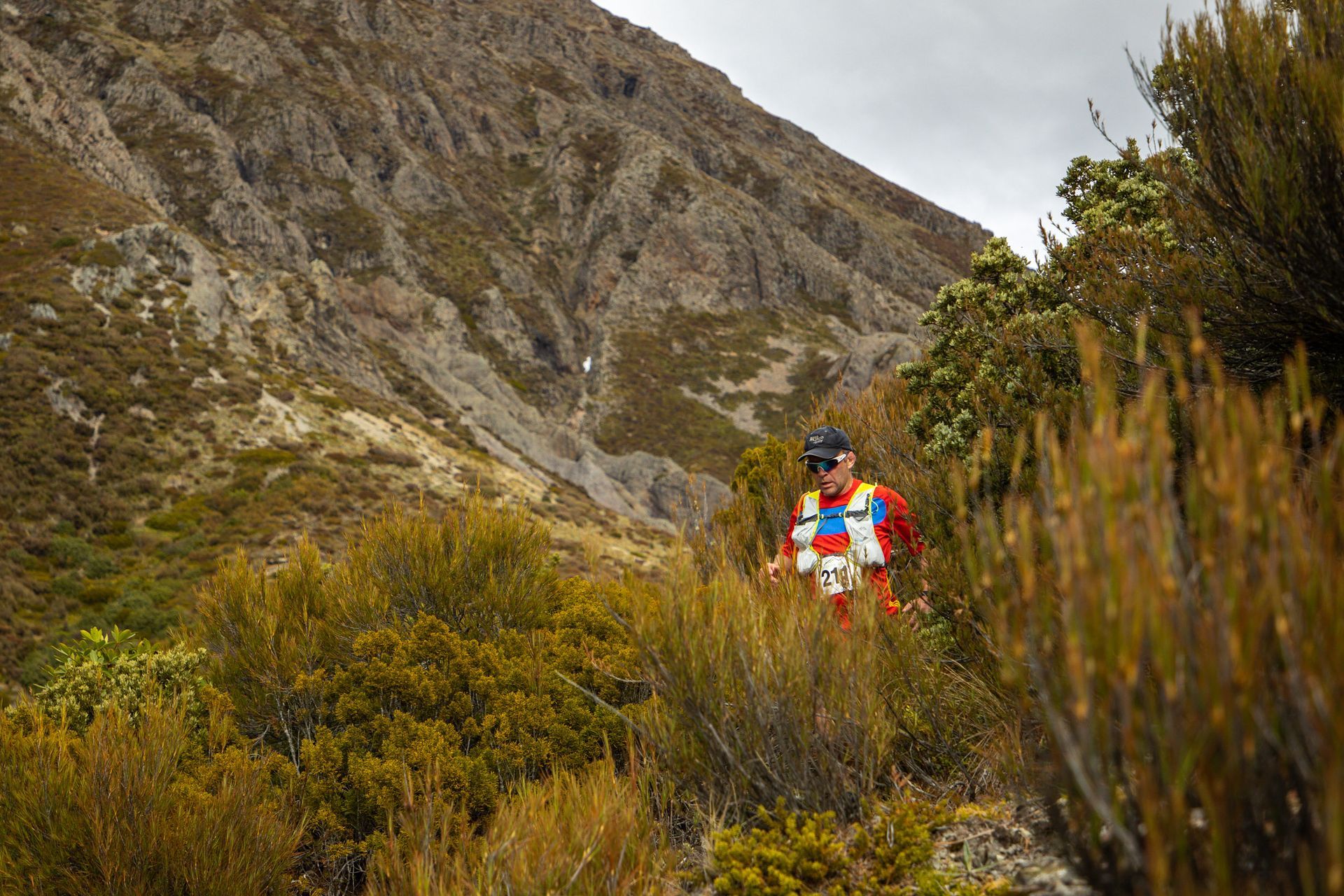 A man is running on a trail in the mountains.