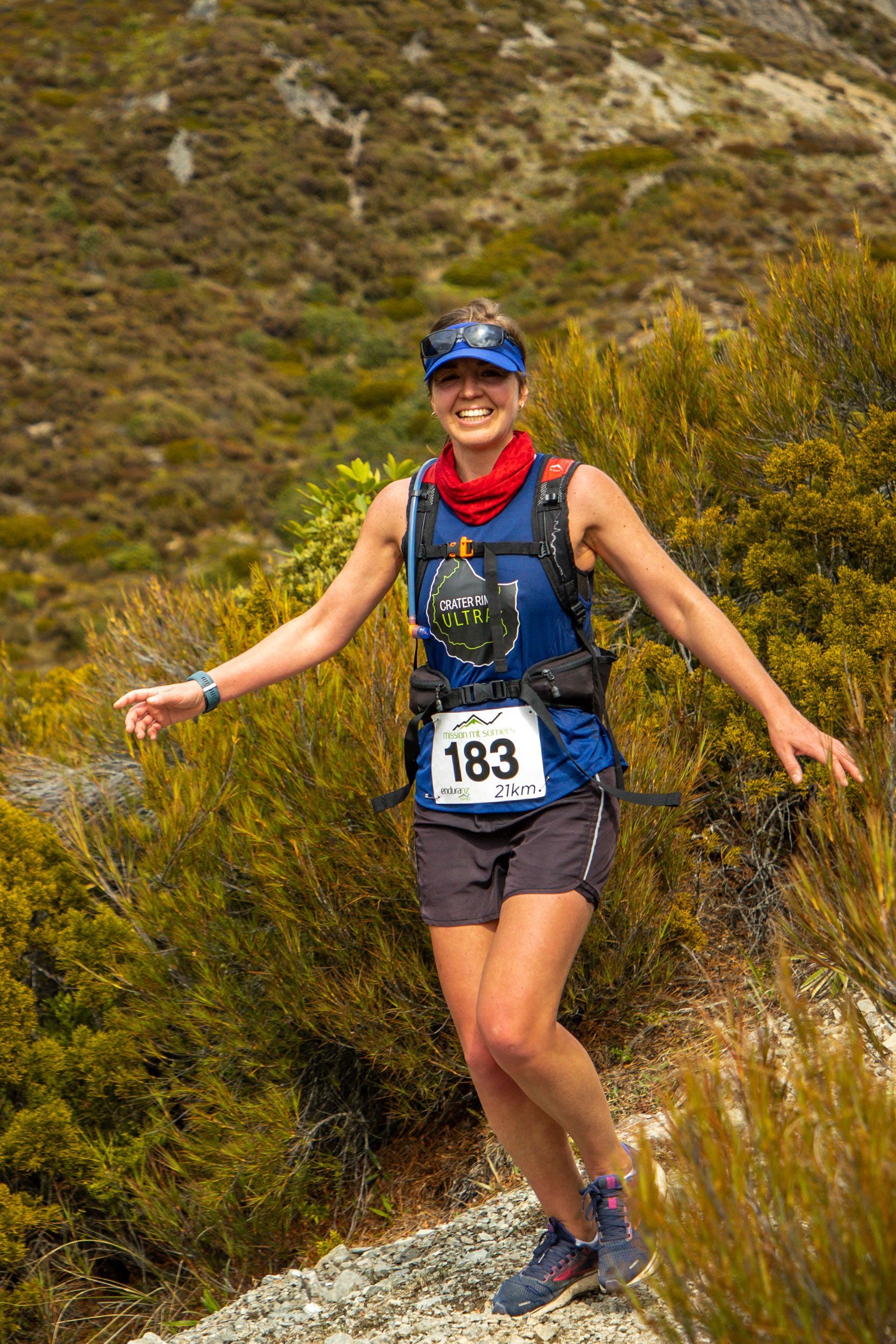 A woman is running on a trail in the mountains.