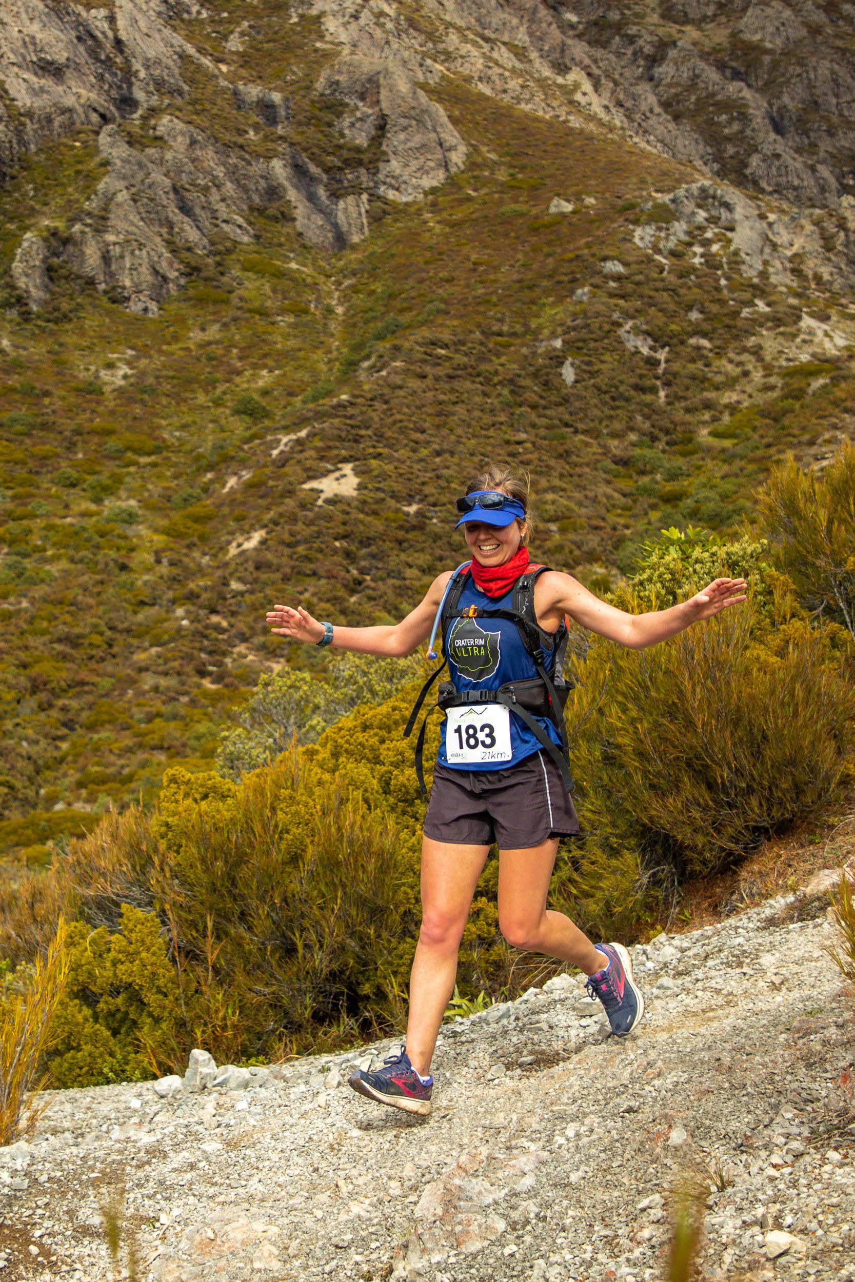 A woman is running on a trail in the mountains.