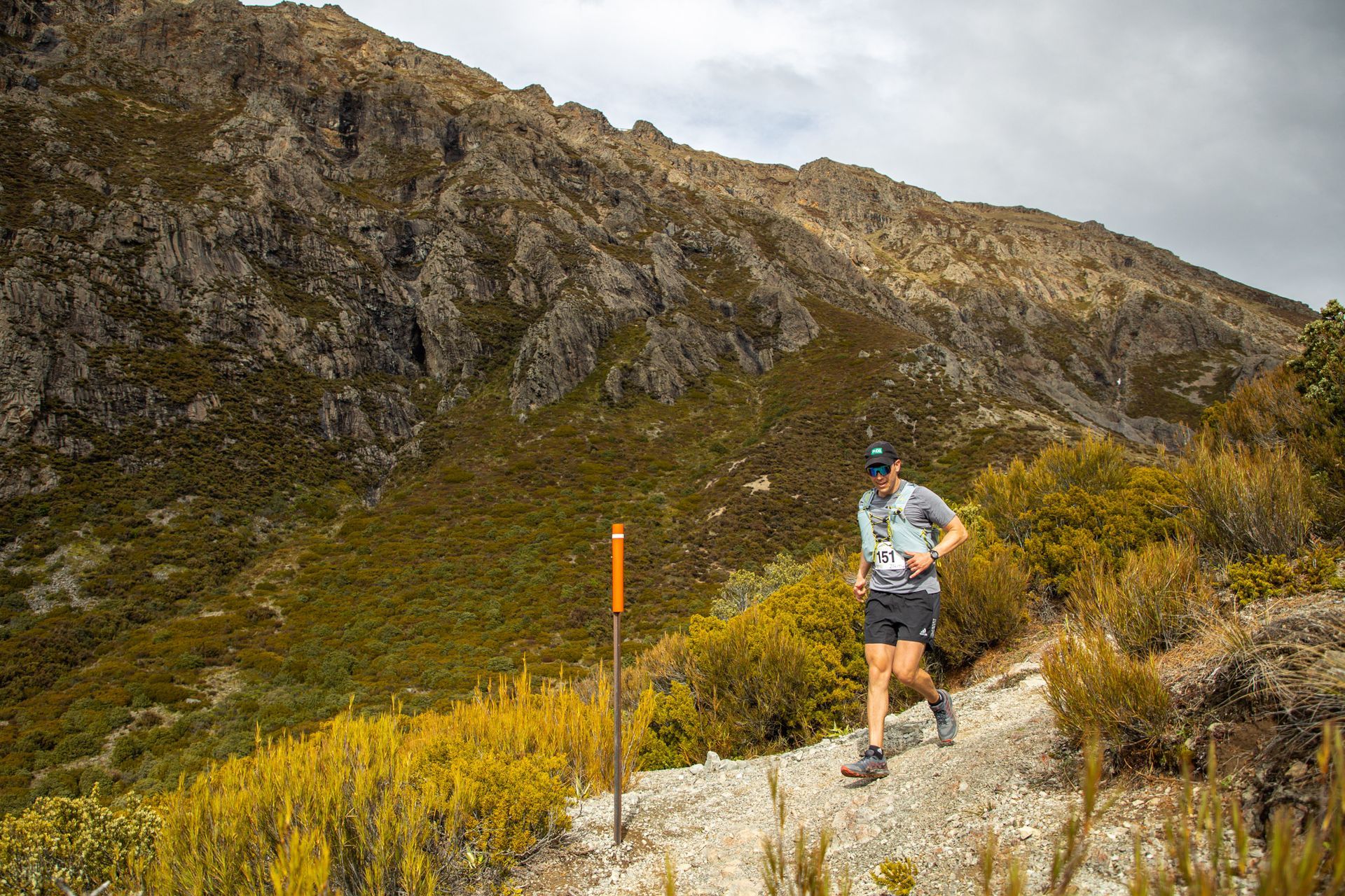 A man is running on a trail in the mountains.