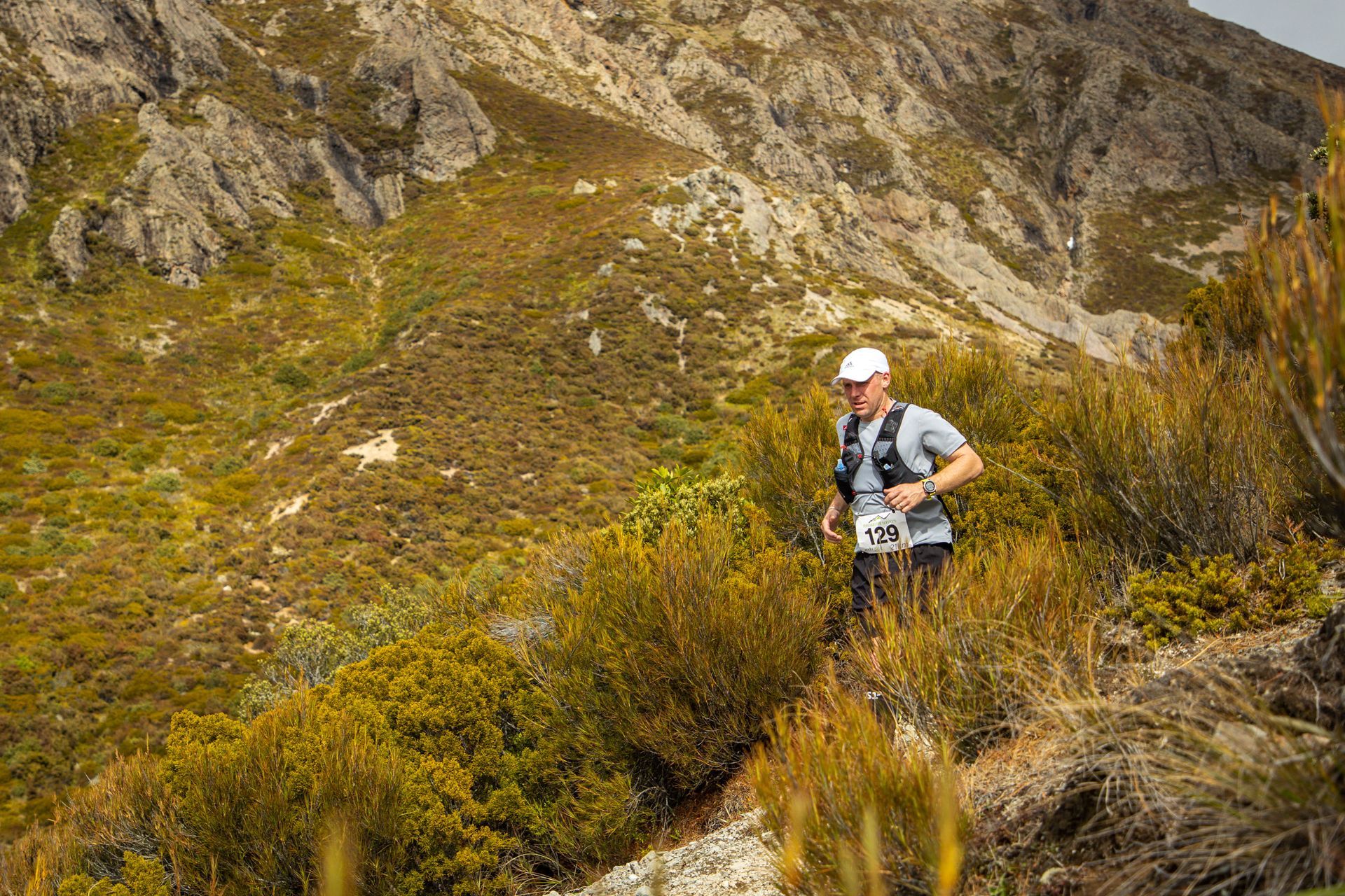 A man is running on a trail in the mountains.