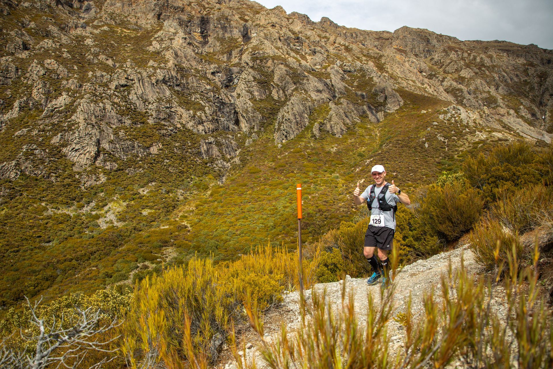 A man is running on a trail in the mountains.