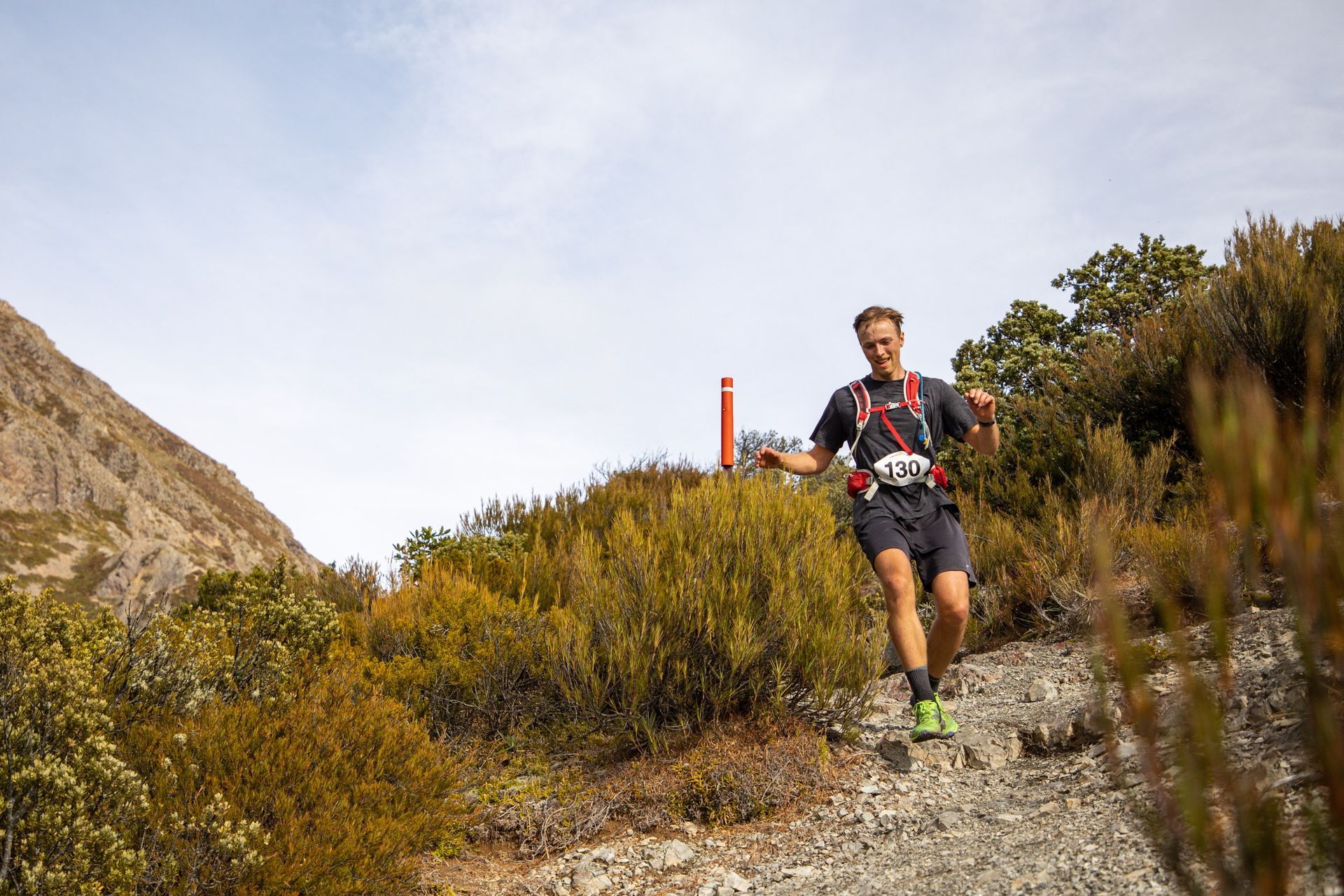 A man is running on a trail in the mountains.