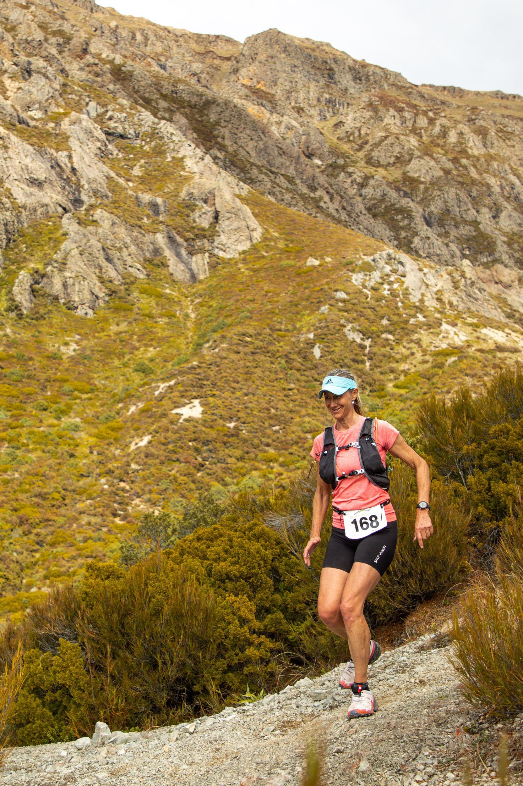 A woman is running on a trail in the mountains.