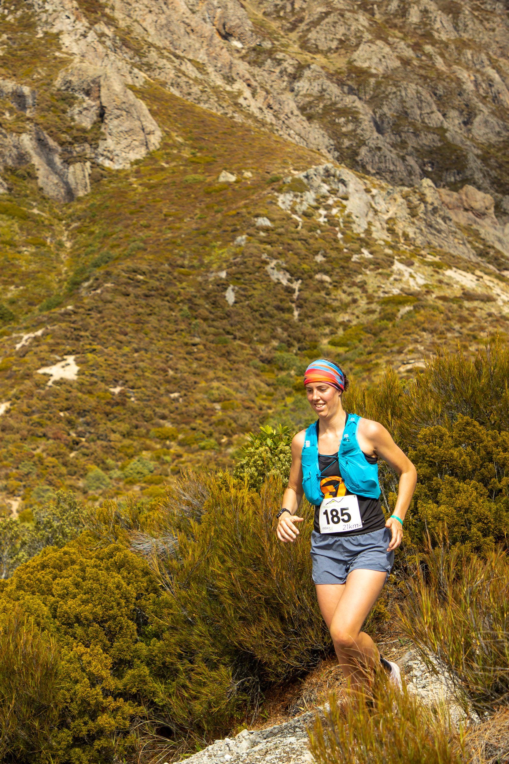A woman is running up a hill in the woods.