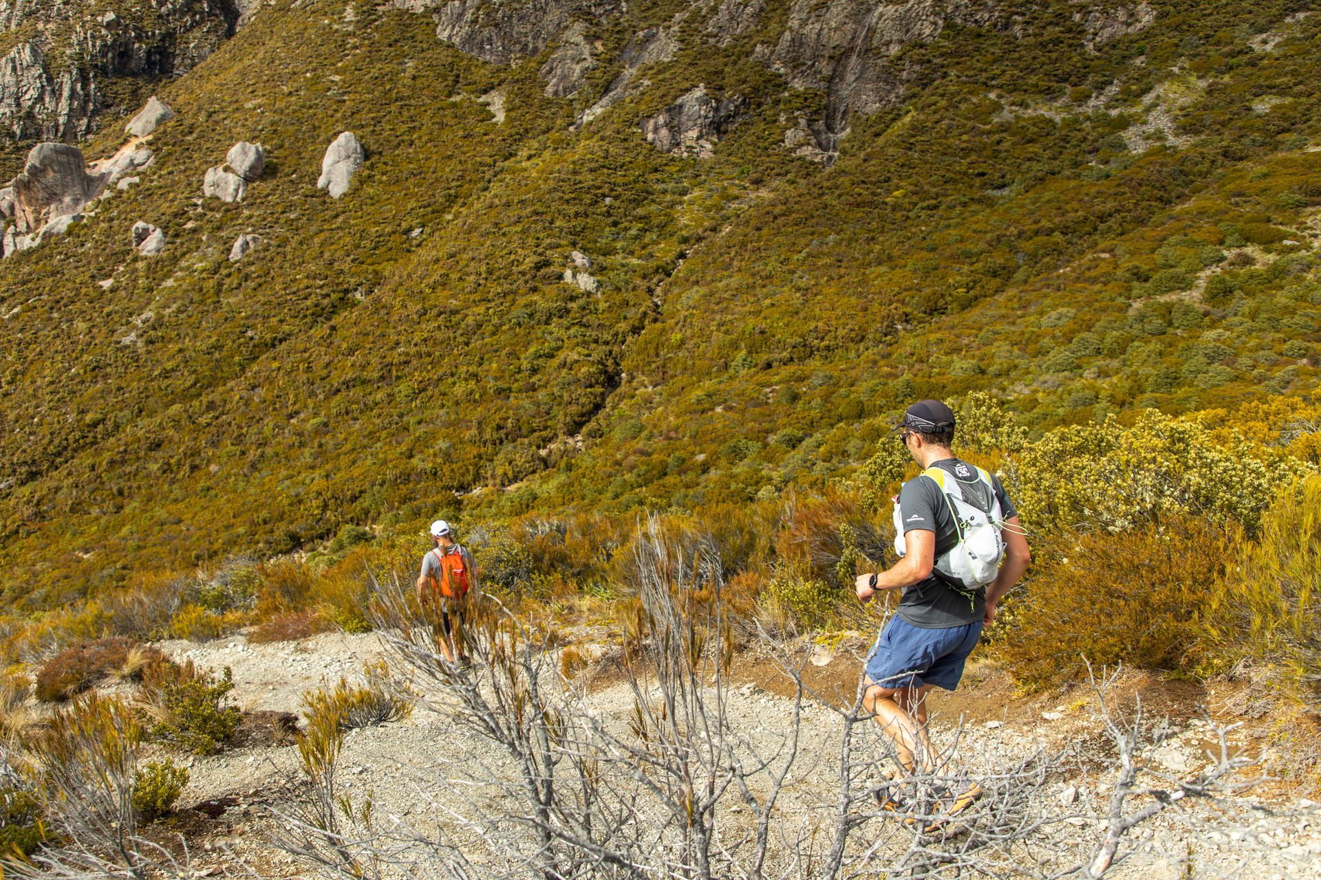 A man and a woman are hiking up a hill.