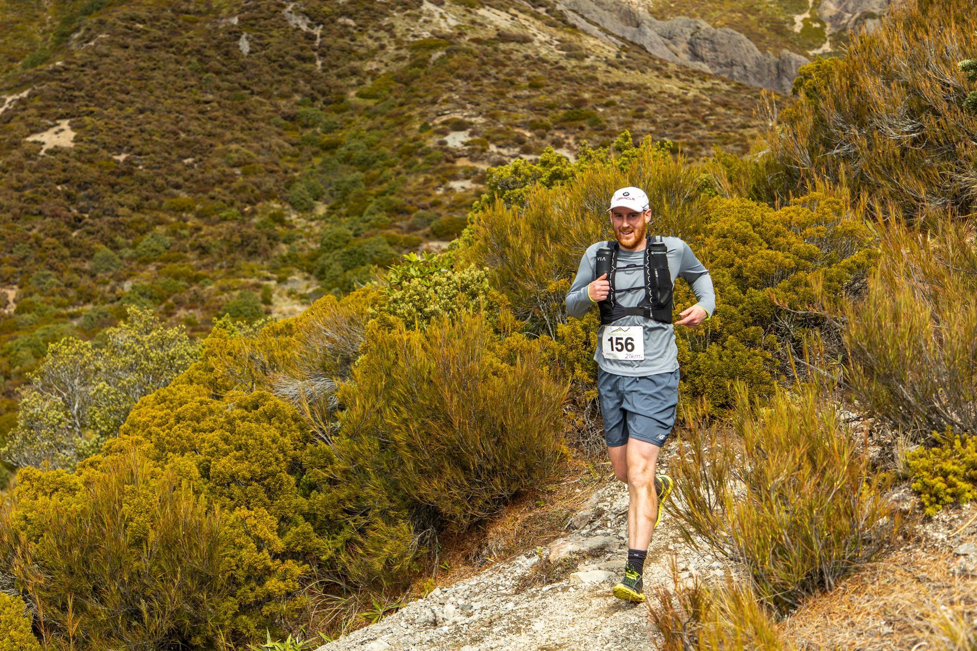 A man is running on a trail in the mountains.