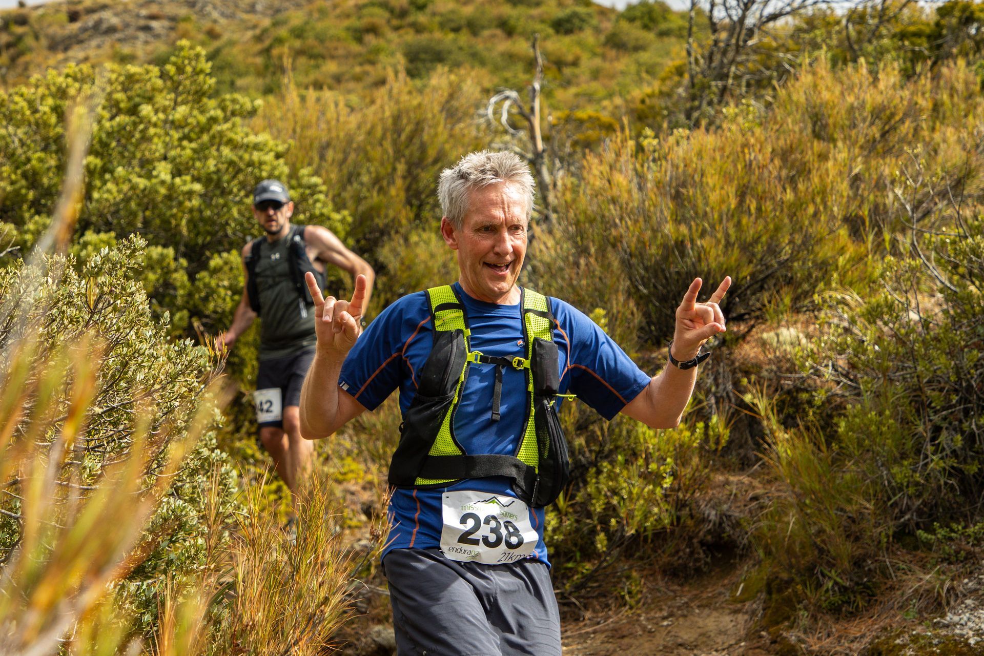 A man is running on a trail in the woods.