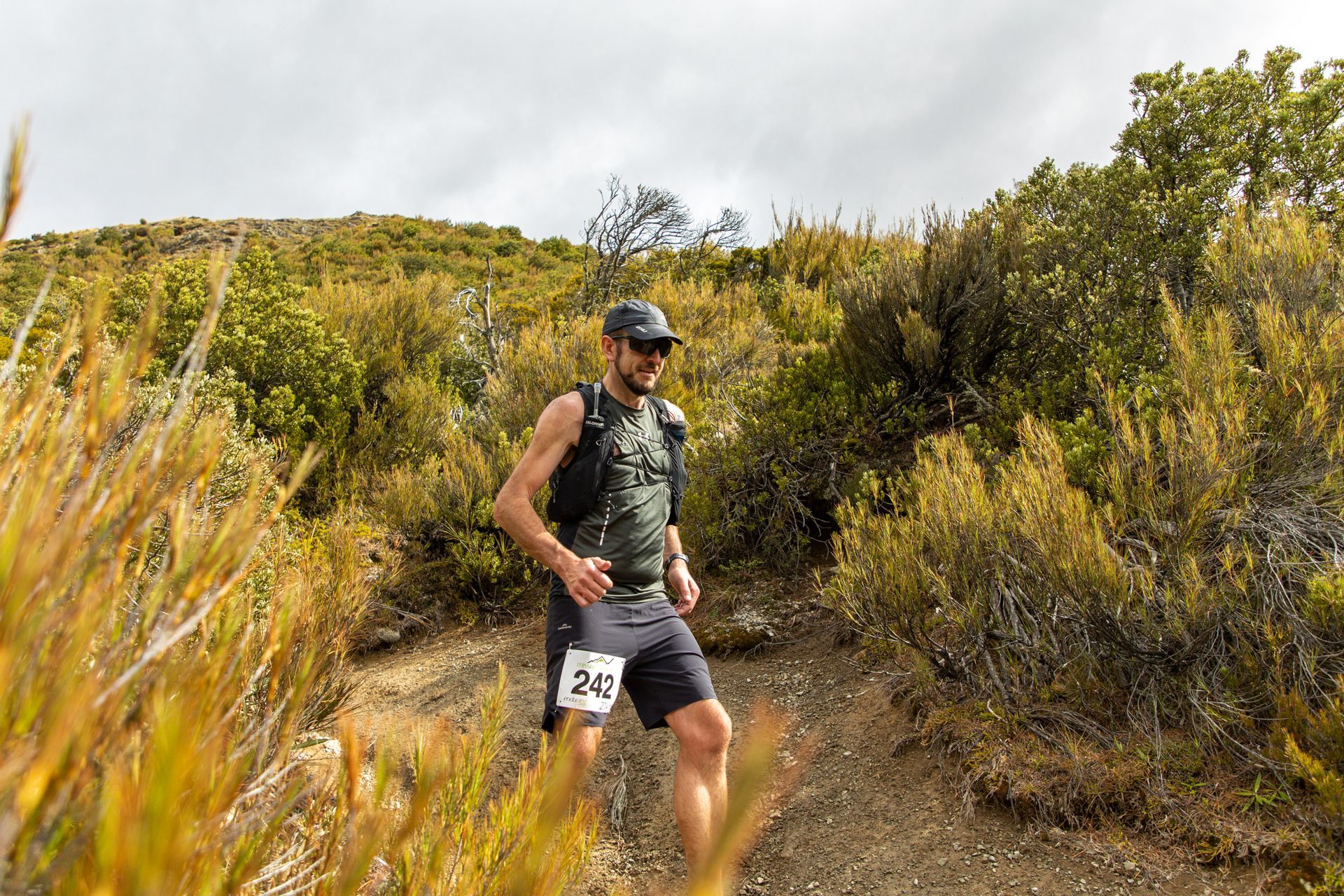 A man is running on a trail in the woods.