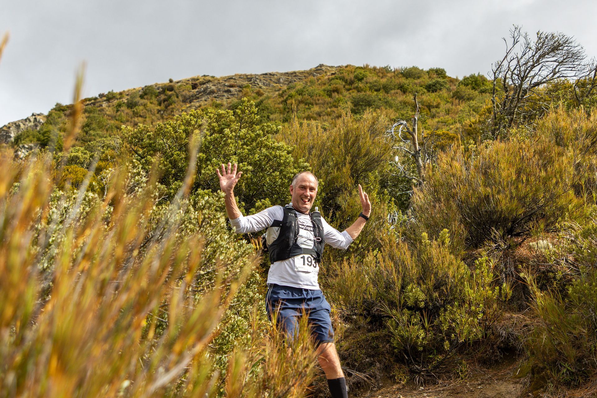A man is standing on top of a hill with his arms in the air.