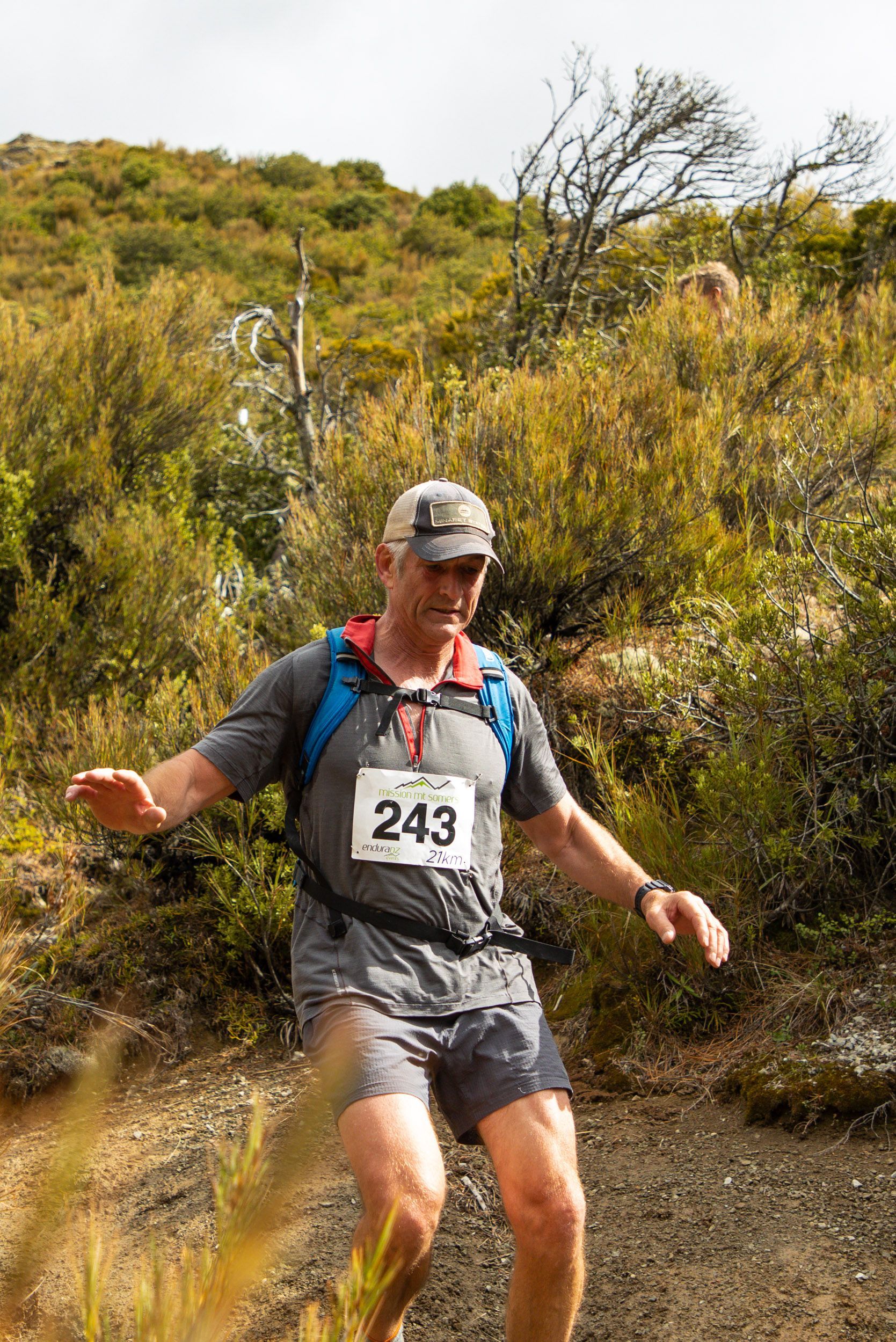 A man is running on a trail in the woods.