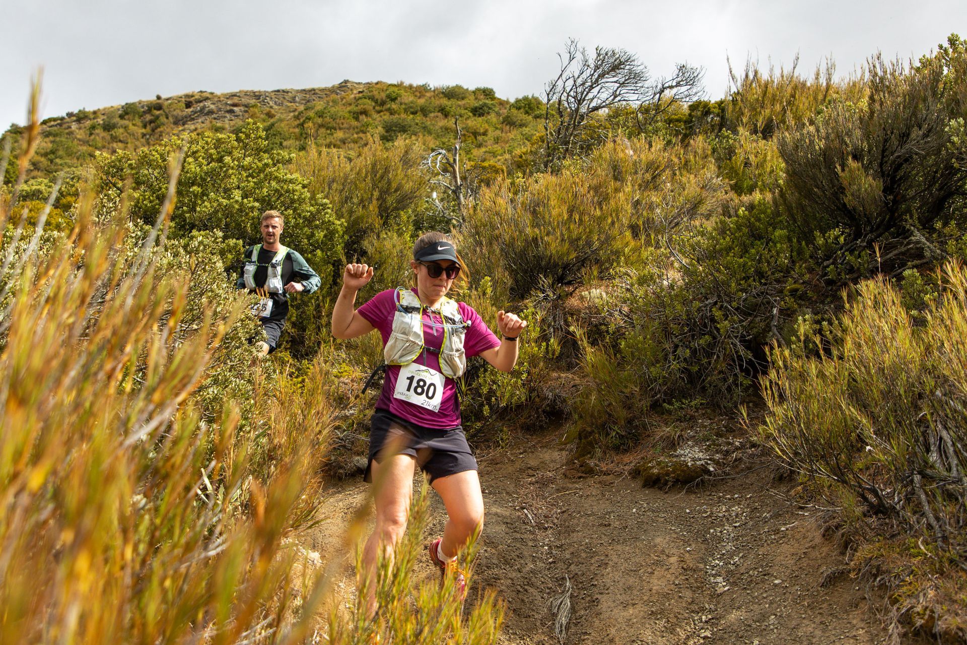 A woman is running on a trail in the woods.