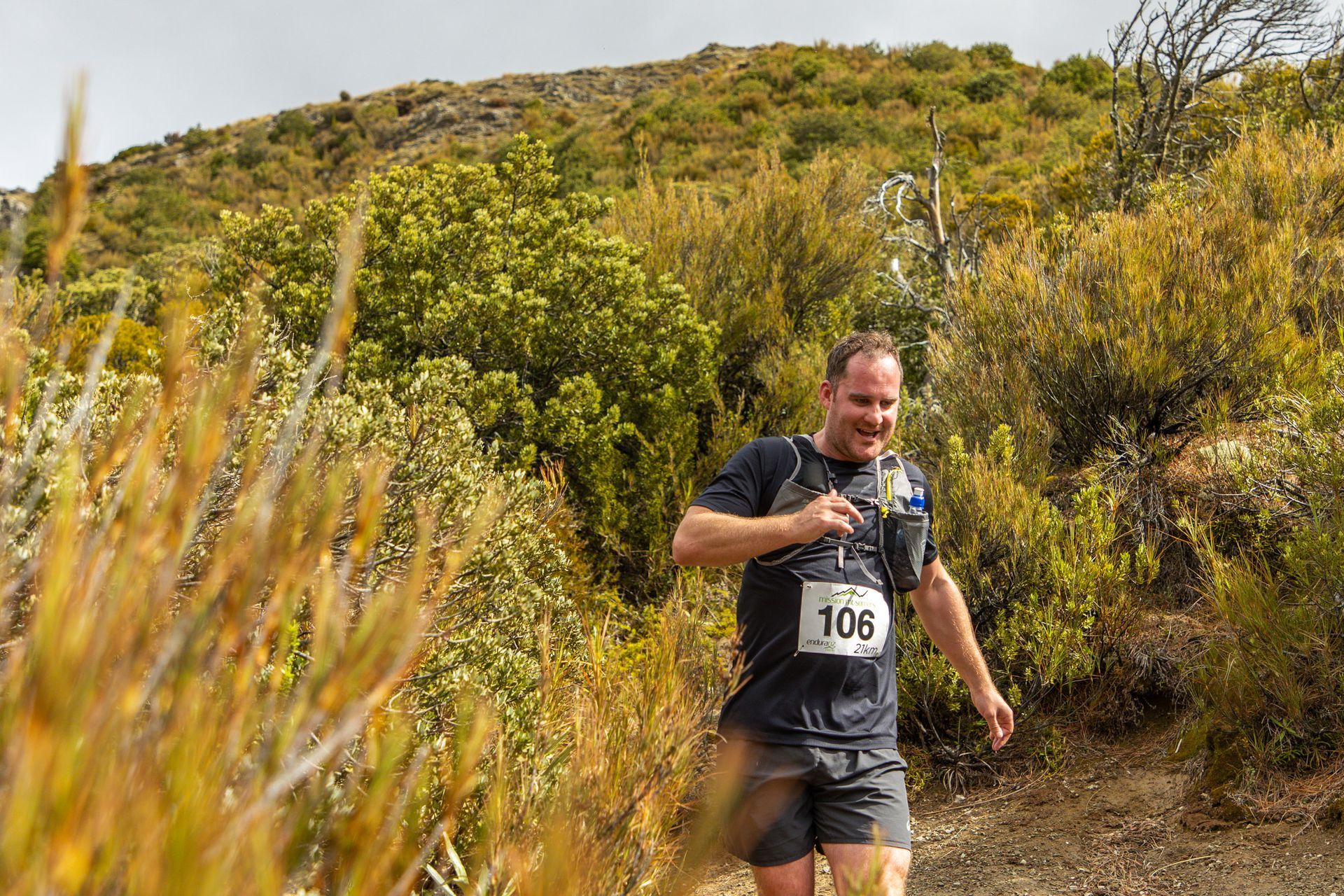 A man wearing a number 105 shirt is running on a trail.