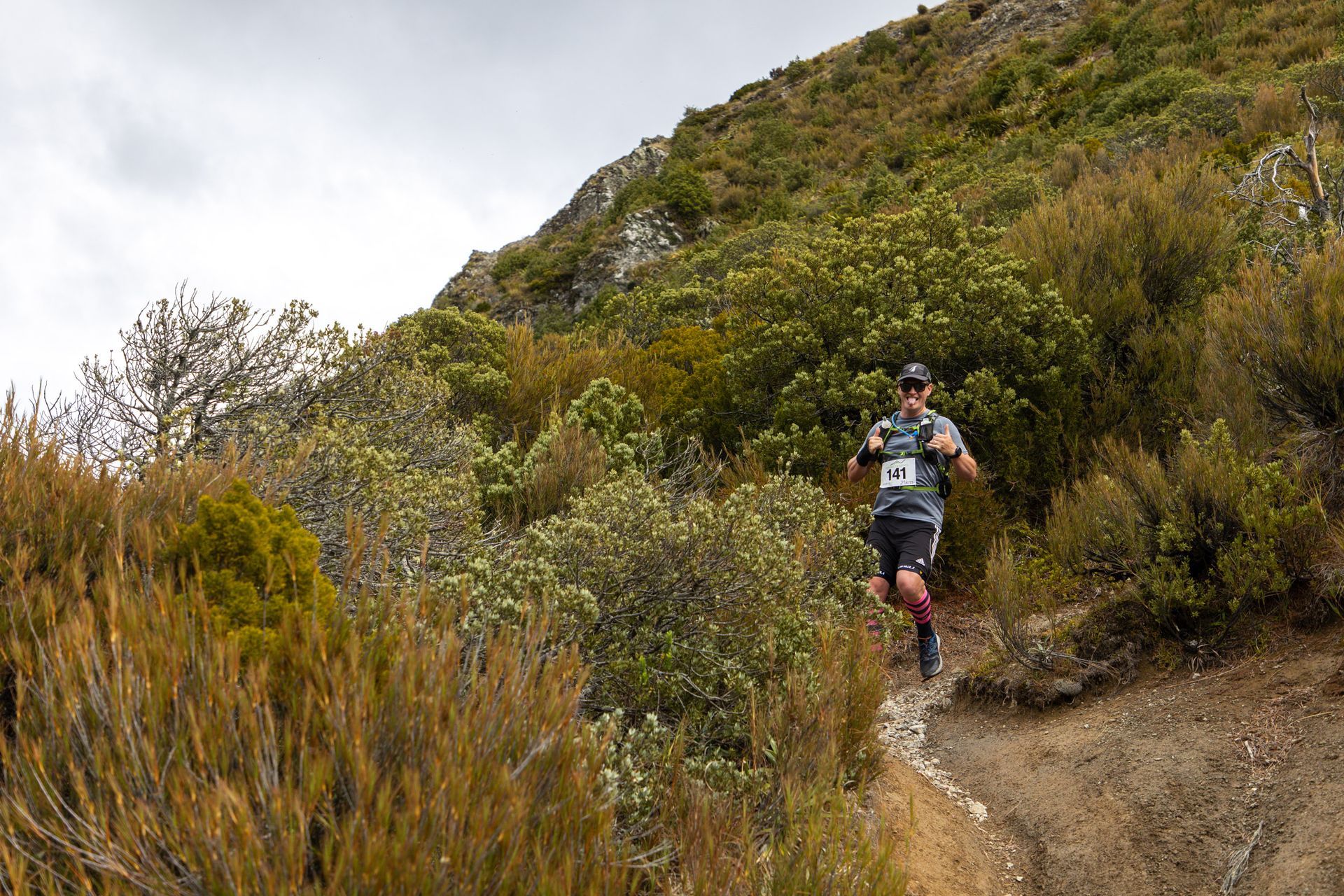 A man is running up a hill on a trail.