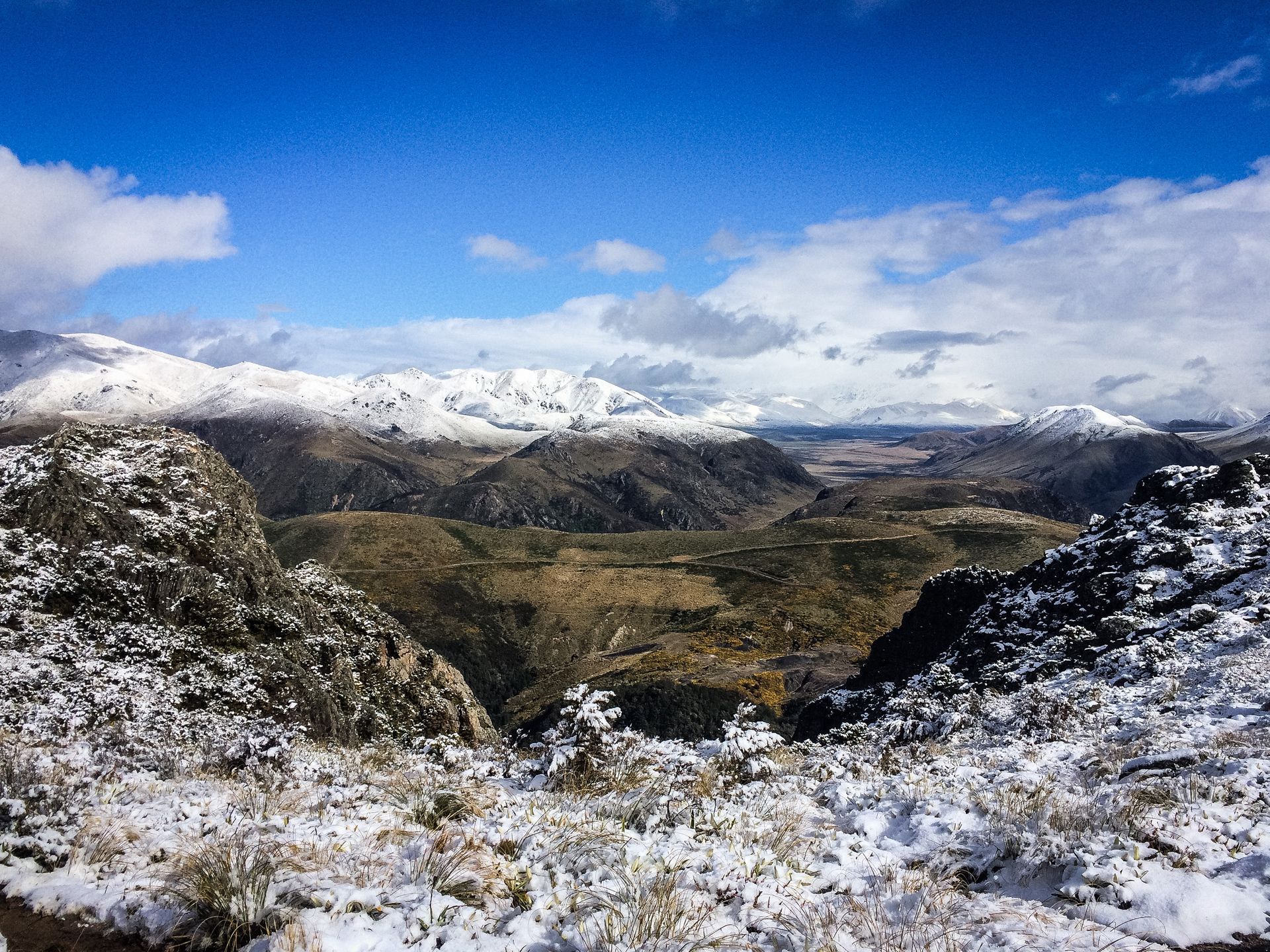 A snowy landscape with mountains in the background and a blue sky