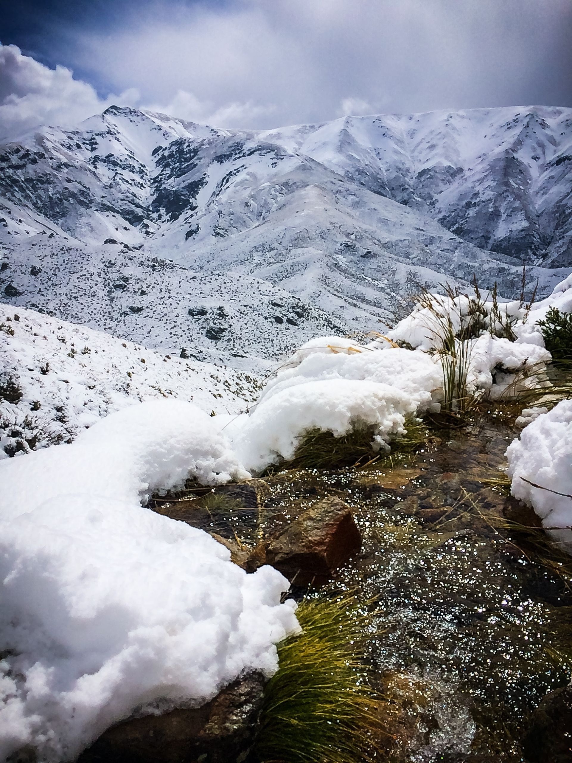 A snowy mountain with a stream running through it