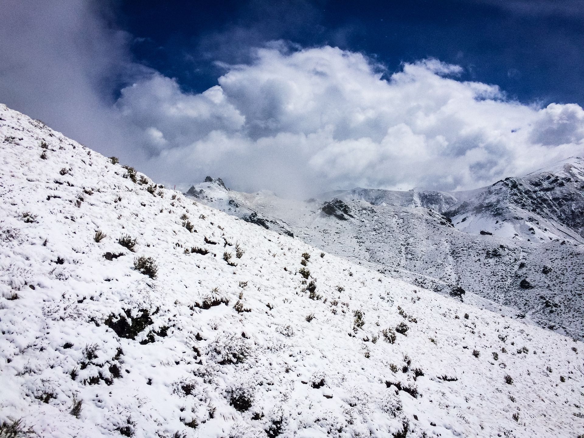 A snowy hillside with a blue sky in the background