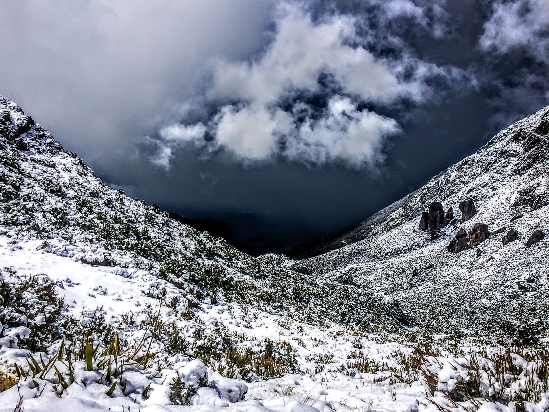 A snowy mountain valley with a cloudy sky in the background.