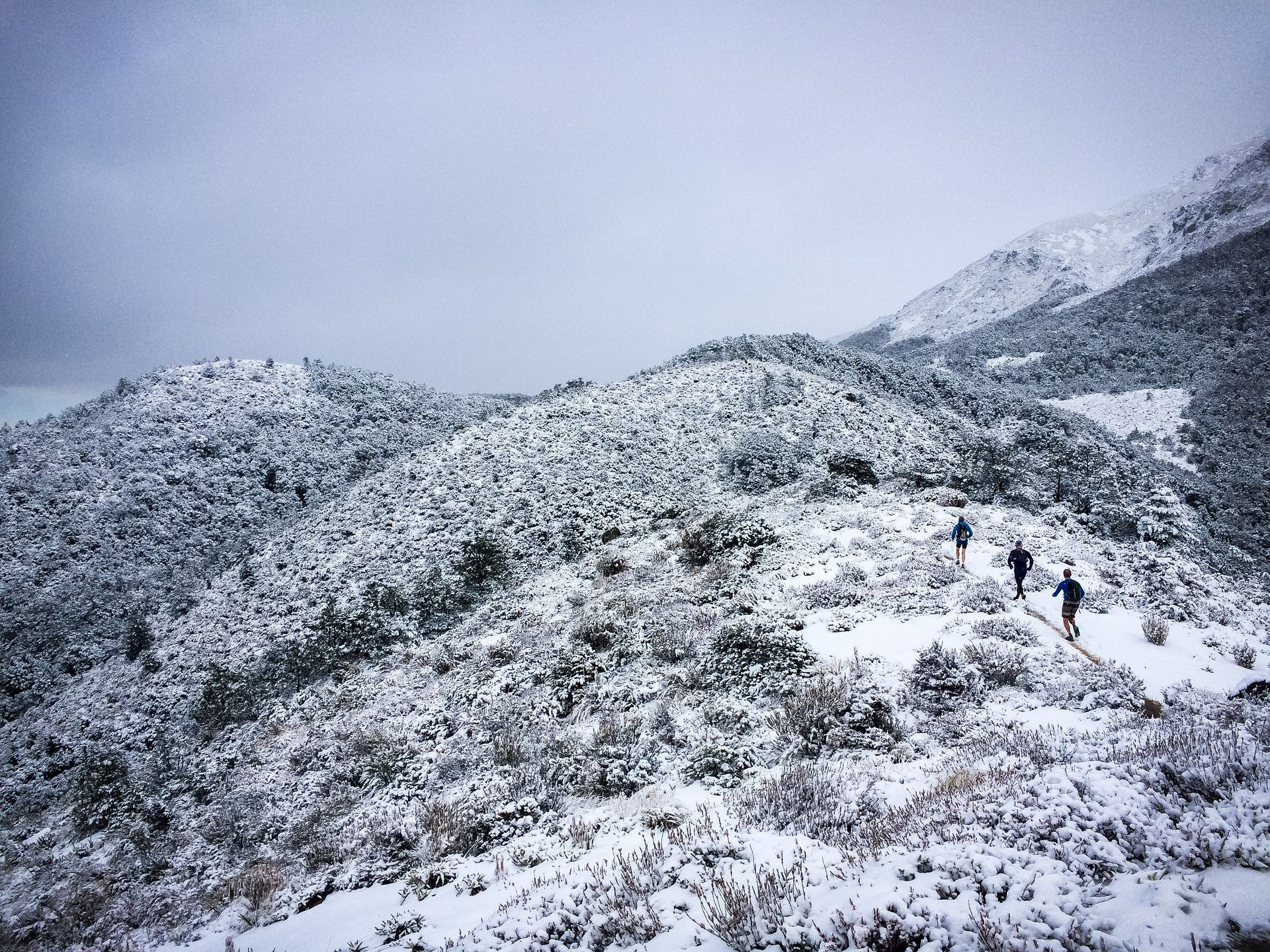 A group of people are walking up a snow covered mountain.