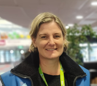 A woman wearing a blue jacket with a green lanyard around her neck