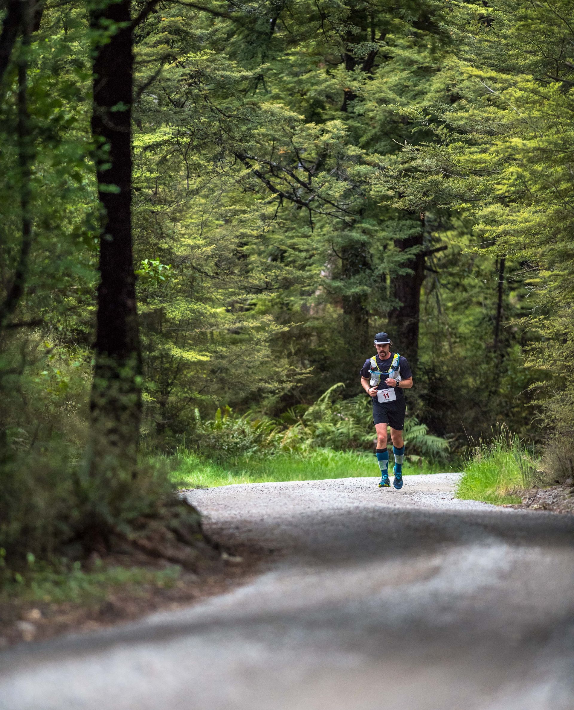 A man is running down a dirt road in the woods.