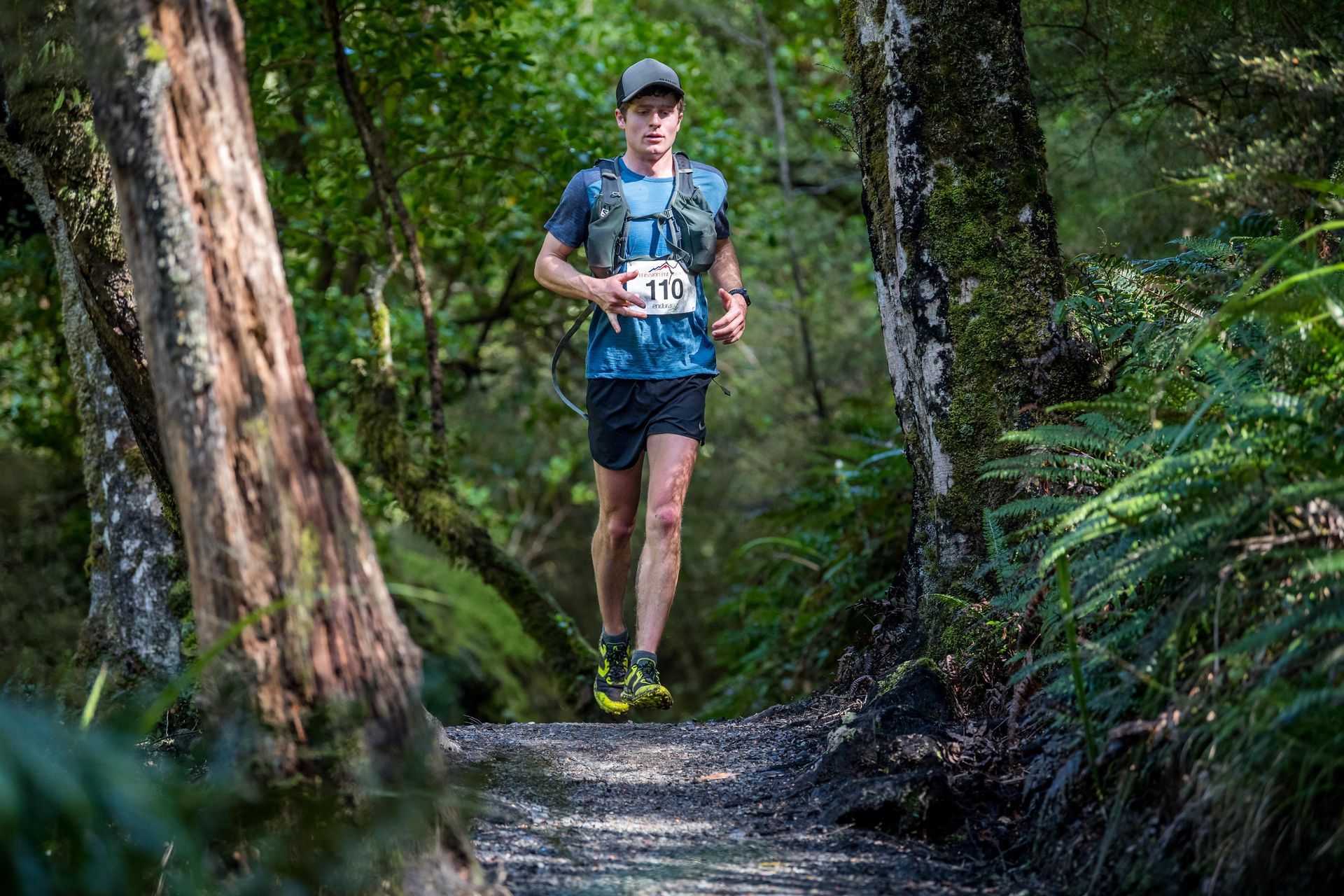 A man is running on a trail in the woods.