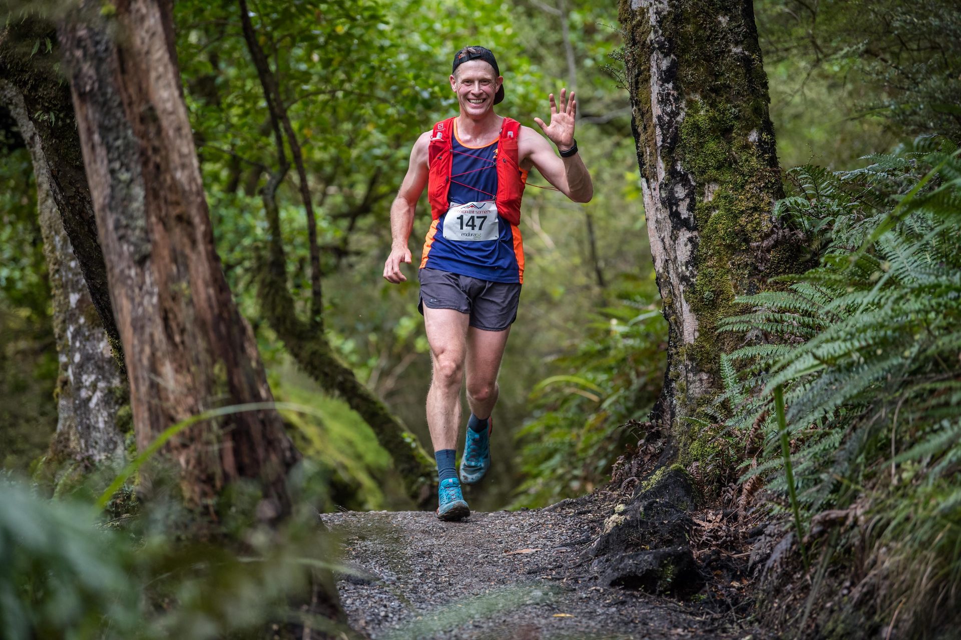 A man is running on a trail in the woods.