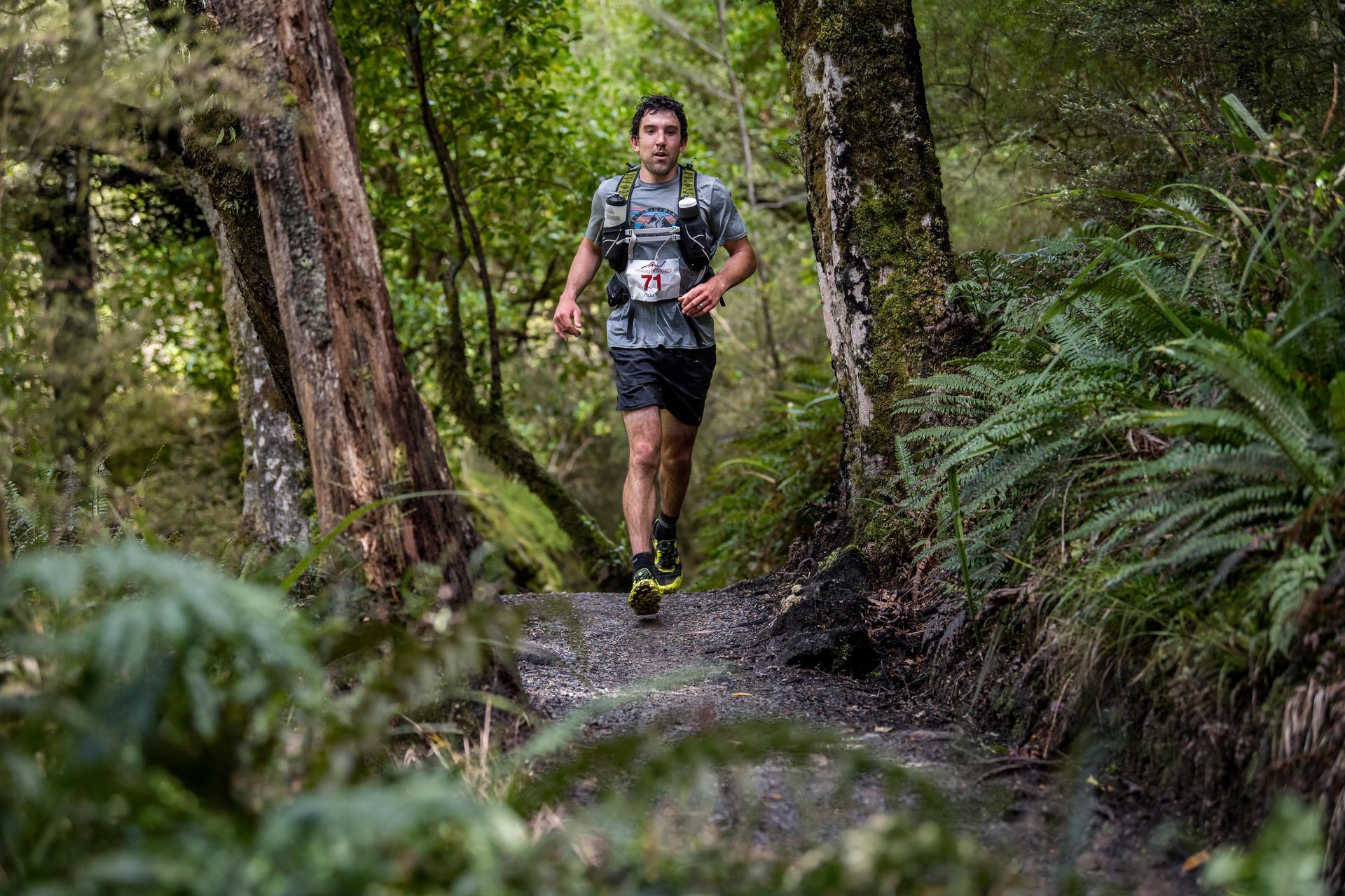 A man is running on a trail in the woods.