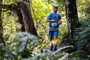 A man is running through a forest on a trail.