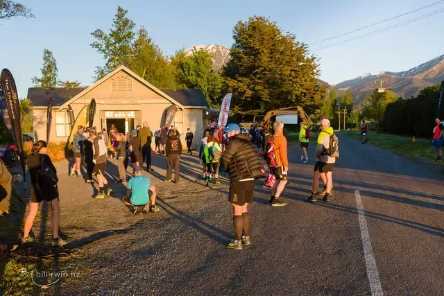 A group of people are standing on the side of a road in front of a building.