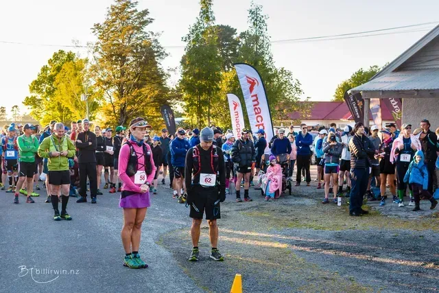A group of people are standing on the side of the road at a race.