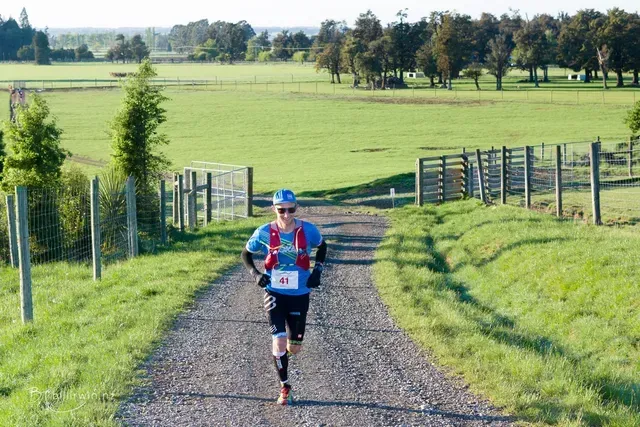A man is running down a dirt road in a field.