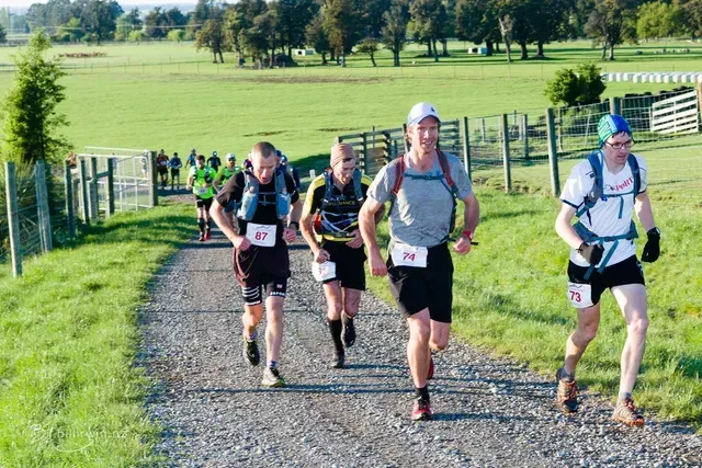 A group of people are running down a dirt road.