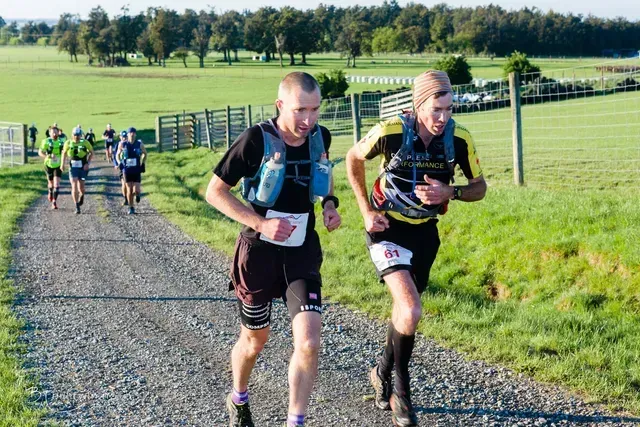 A group of people are running down a dirt road.
