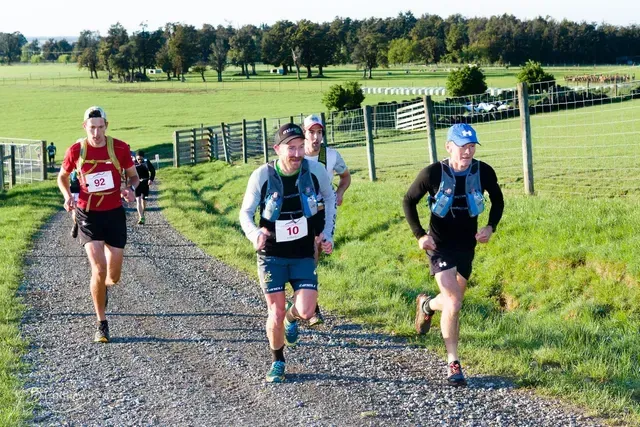 A group of men are running down a dirt road.
