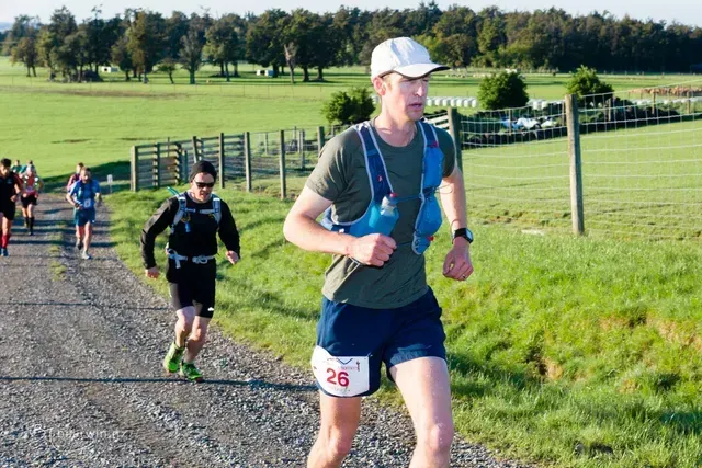 A group of people are running down a dirt road.