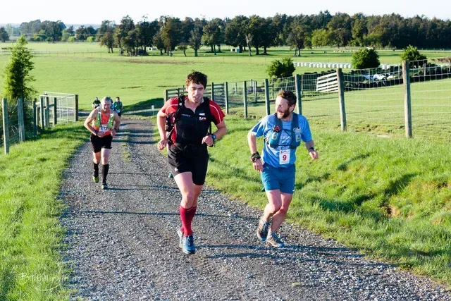 A group of people are running down a dirt road.