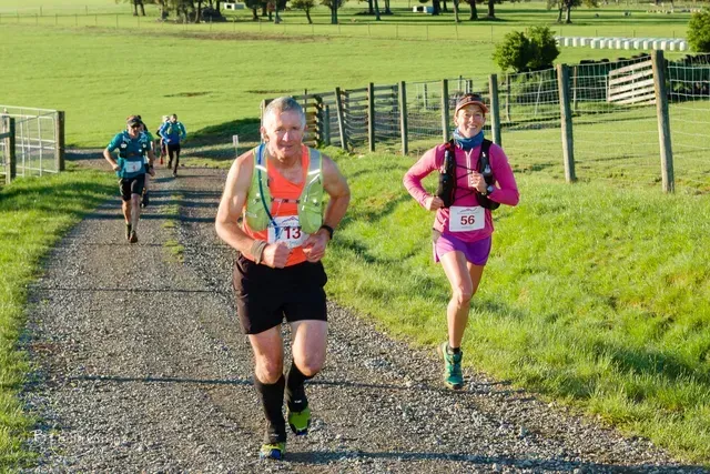 A group of people are running down a dirt road.