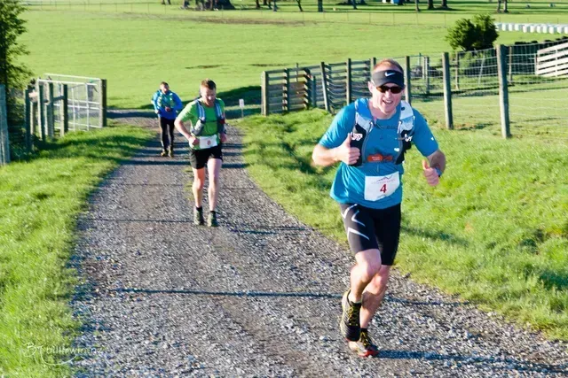 A group of people are running down a dirt road.