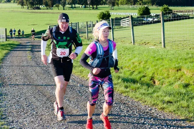 A man and a woman are running down a dirt road.
