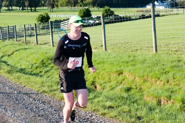 A man is running on a dirt road with a number 50 on his shirt.